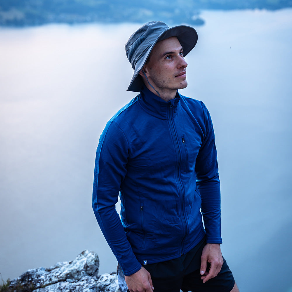 m² steht auf Felsvorsprung, blickt aufs Wasser. Perfekt für Outdoor-Abenteuer, bietet Wärme, Atmungsaktivität und Flexibilität.