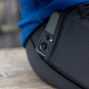 Merino Leggings/Hose Damen - 290 g/m2 mit Smartphone in Seitentasche, auf Holzoberfläche. Ideal für Yoga, Reisen; komfortabel und temperaturregulierend.