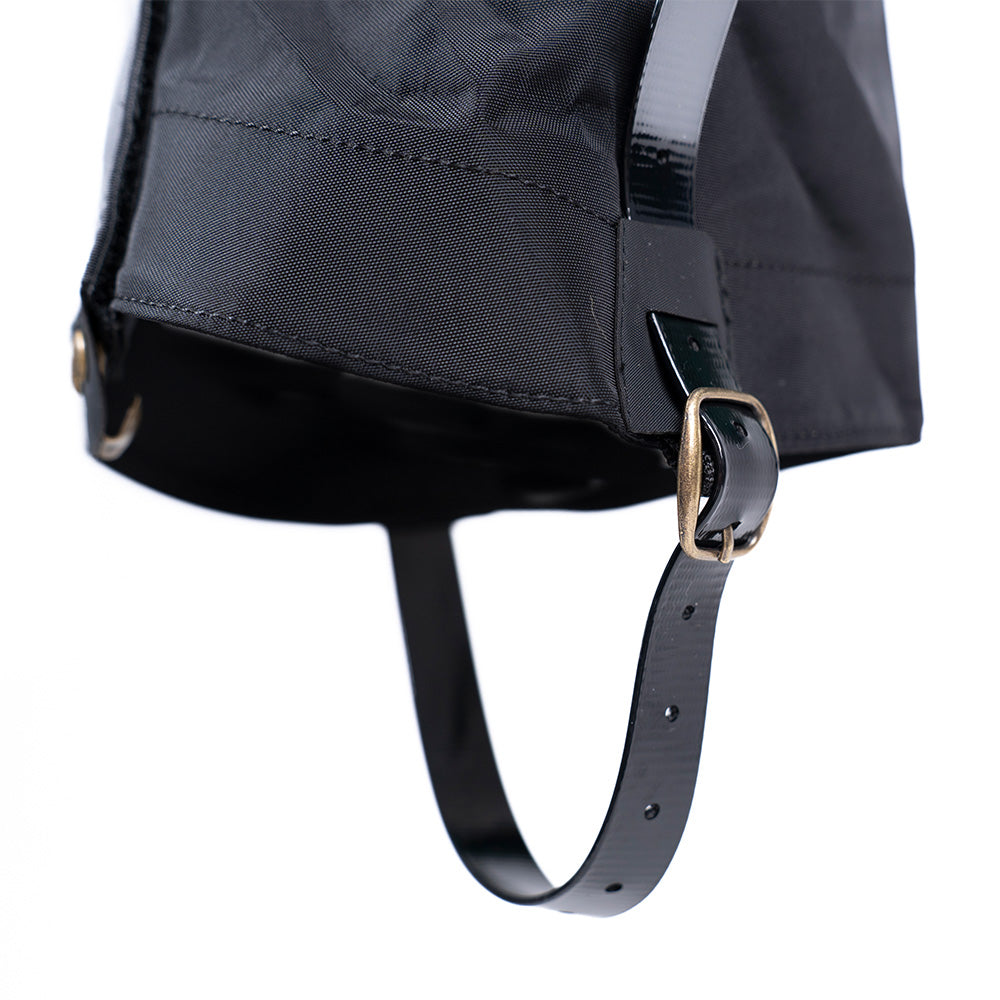 Nahaufnahme einer schwarzen Gamasche mit glänzendem, verstellbarem Riemen und Messingschnalle, ideal für Outdoor-Abenteuer. Perfekt für nasse Bedingungen beim Wandern.