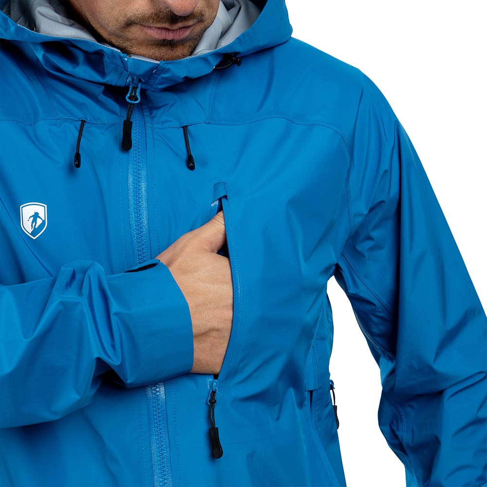 Person trägt Herren 3 Lagen Hardshell Regenjacke mit wasserdichtem Reißverschluss und Logo. Hand greift in Brusttasche. Ideal für Outdoor-Aktivitäten.