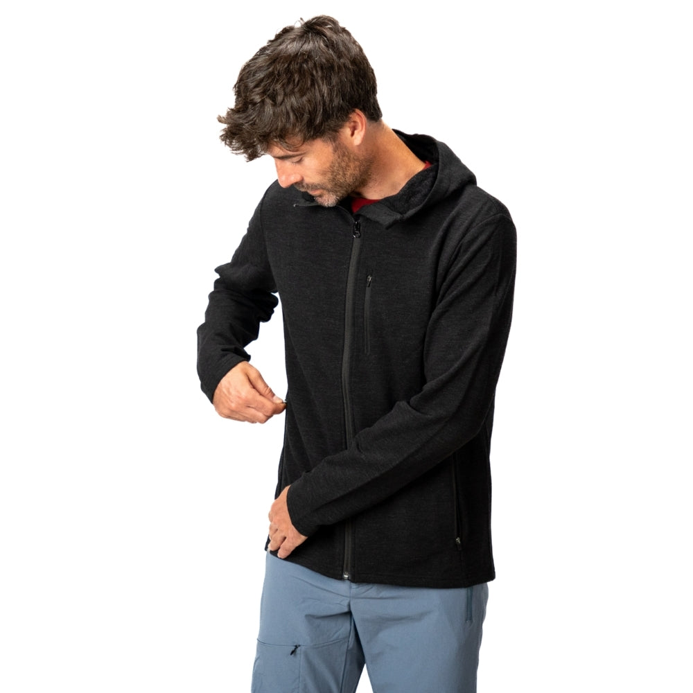 Modell trägt Merino Hoody Herren - 270 g/m2, schwarzen Kapuzenpulli mit Reißverschlusstaschen, ideal für Outdoor-Aktivitäten und kältere Bedingungen.