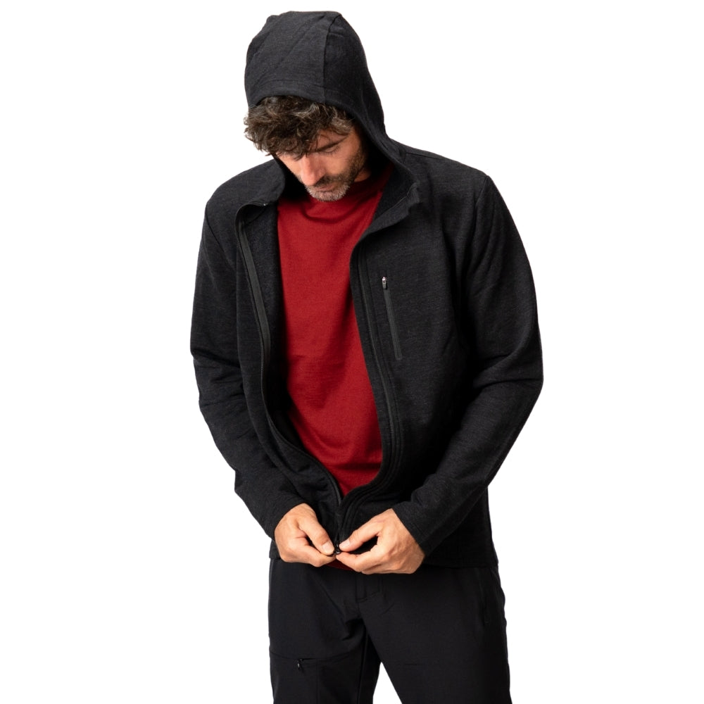 Merino Hoody Herren - 270 g/m²: Mann mit Kapuze, zieht schwarzen Hoodie über rotem T-Shirt zu. Ideal für Outdoor-Aktivitäten, atmungsaktiv und elastisch.