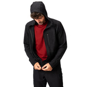 Merino Hoody Herren - 270 g/m²: Mann mit Kapuze, zieht schwarzen Hoodie über rotem T-Shirt zu. Ideal für Outdoor-Aktivitäten, atmungsaktiv und elastisch.