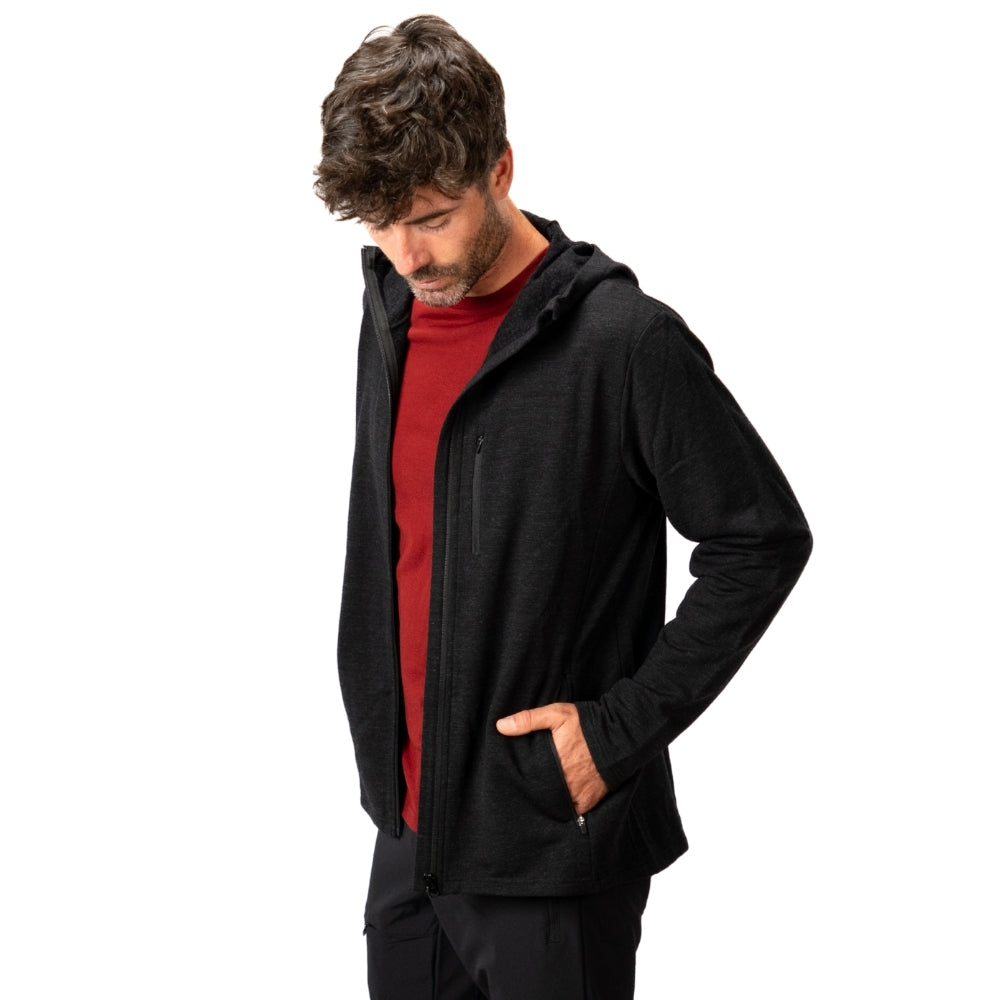 Erwachsener Mann trägt Merino Hoody Herren - 270 g/m², schwarze Kapuze, dunkles rotes Shirt, Hand in der Tasche, ideal für Outdoor-Aktivitäten bei kälteren Bedingungen.