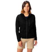 Frau trägt 100% Merino Sport Hoody mit Zip Damen - 230g/m2, locker geschnitten, mit Brusttasche und YKK-Reißverschluss, ideal für Outdoor-Aktivitäten und Reisen.