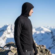 Schwarzer Merino Hoodie Herren 230 g/m² mit Kapuze am verschneiten Gipfel