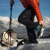 Dame zieht sich die Chain Pro 18 Grödel an für ihre Winterwanderung im Schnee