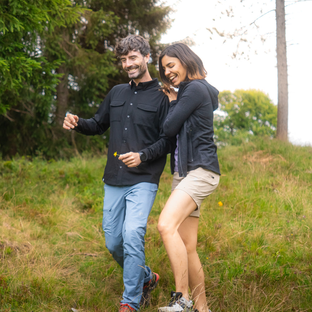 Paar in Outdoor-Kleidung im Wald, Frau trägt Merino Hoody Damen - 270g/m2, ideal für Outdoor-Aktivitäten bei kühlem Wetter.