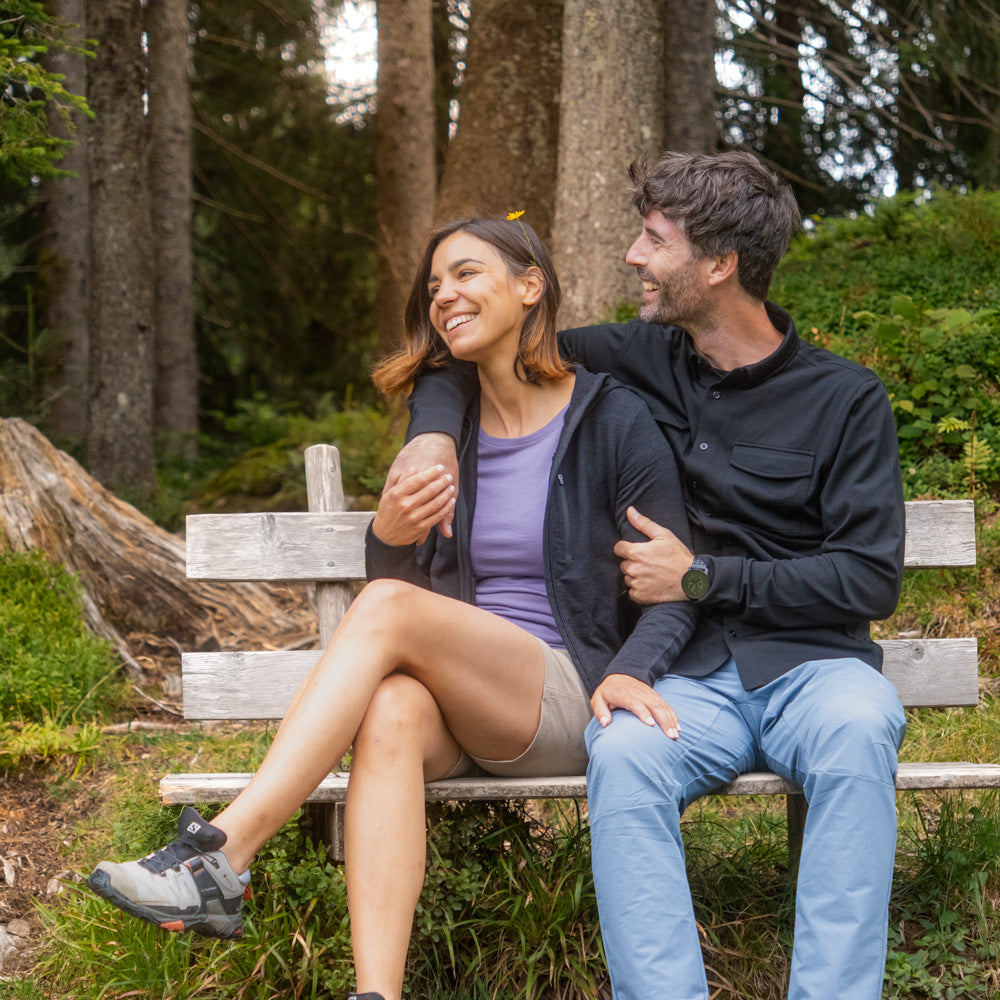 Merino Hoody Damen - 270g/m²: Paar auf Holzbank im Wald, Frau trägt funktionalen Hoody, ideal für Outdoor-Aktivitäten. Natürliche Merinowolle, atmungsaktiv und elastisch.