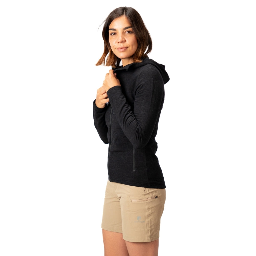 Frau trägt Merino Hoody Damen - 270g/m² mit Kapuze, zeigt sportliche Funktionalität für Outdoor-Aktivitäten; kombiniert Merinowolle, Bambus-Viskose und Spandex für Komfort.