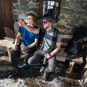 Zwei Wanderer sitzen auf einer Bank, der rechte trägt das Merino Coolmax Polo von Alpin Loacker - ideal für Outdoor Aktivitäten