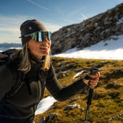 Frau trägt graue Merino Mütze beim wandern in Bergkulisse