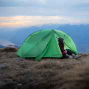 Frau sitzt in ultraleichtem Lumen 1 Zelt für eine Person mit Aussicht auf die Berge