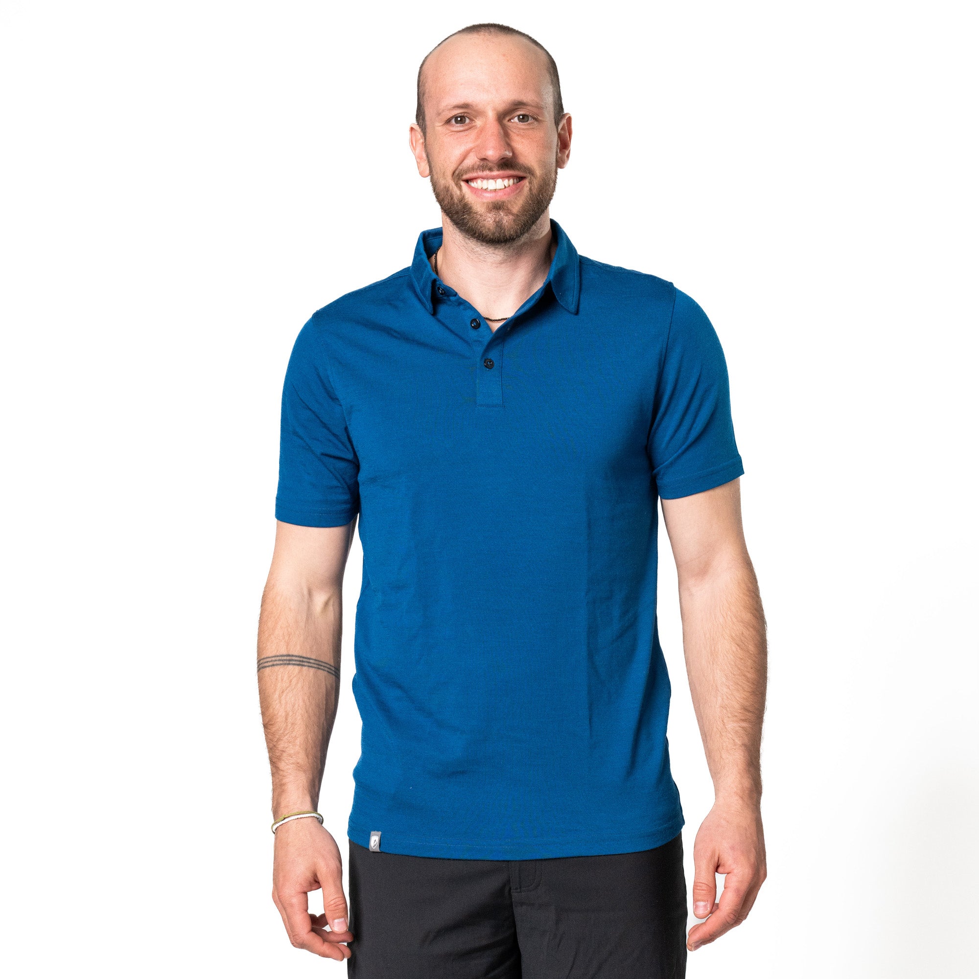 Model posiert in blauem Merino Coolmax Polo vor weißem Hintergrund