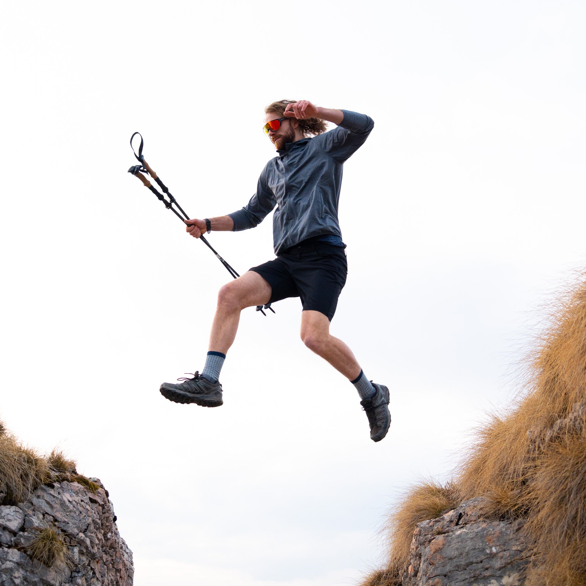 Model Springt mit kurzer Wanderhose von Alpin Loacker über einen Felsspalt