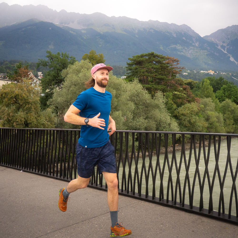 Mann joggt mit blauem Merino Coolmax T-Shirt über eine Brücke
