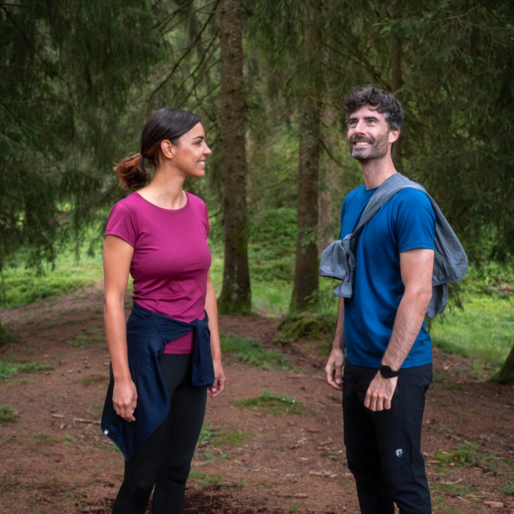 Paar auf Waldweg, trägt das Alpin Loacker 100% Merino T-Shirt Damen 160 g/m²- ultrafein, ideal für Outdoor-Aktivitäten aufgrund Komfort und Funktionalität.
