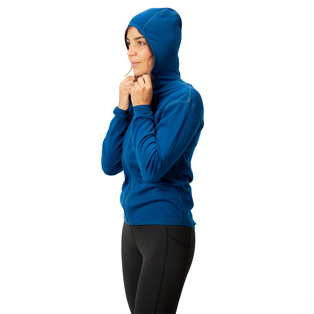 Frau in 100% Merino Sport Hoody mit Zip Damen - 230g/m2, Kapuze auf, hält Kordeln. Ideal für Outdoor-Aktivitäten, atmungsaktiv, temperaturregulierend.