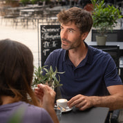 Mann in Merino Polo Shirt Herren genießt Kaffee im Freien. Das stilvolle, atmungsaktive Shirt von alpinloacker.com ist ideal für Outdoor-Aktivitäten und Alltag.