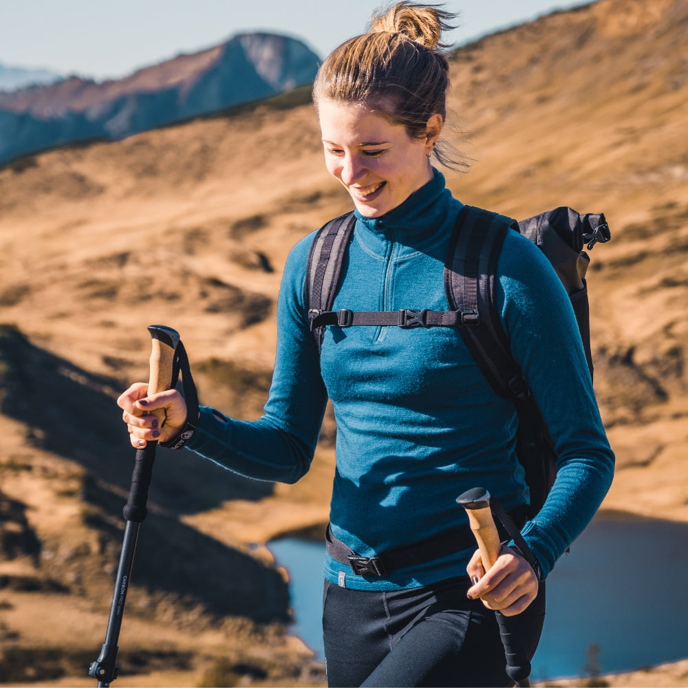 Frau beim Wandern in den Bergen, trägt das Merino Langarmshirt mit Zip Damen 230g/m² von Alpin Loacker, ideal für Outdoor-Abenteuer.