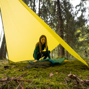 Frau im Zelt mit Tarp 500, leichtes, vielseitiges Wingtarp für Outdoor-Abenteuer, bietet Regen- und Sonnenschutz, ideal für 1-2 Personen.
