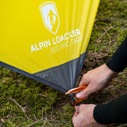 Person befestigt das Tarp 500 - das leichte Wingtarp, ideal für Outdoor-Abenteuer, als Schutz vor Regen und Sonne. Perfekt für 1-2 Personen.