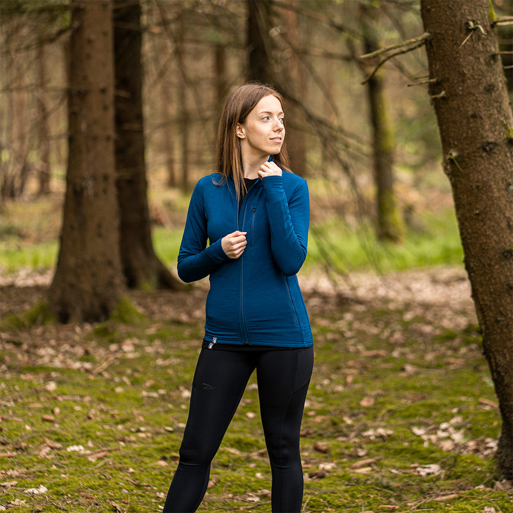 Frau im Wald trägt die Merino Jacke Damen 270 g/m², perfekt für Outdoor-Aktivitäten, aus Merinowolle und Bambusfasern für Komfort und Funktionalität.