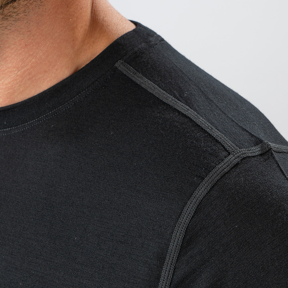 Merino Langarmshirt mit Zip Herren 230 g/m², Nahaufnahme eines Mannes mit schwarzem Shirt, ideal für Outdoor-Aktivitäten dank Atmungsaktivität und Komfort aus hochwertiger Merinowolle.