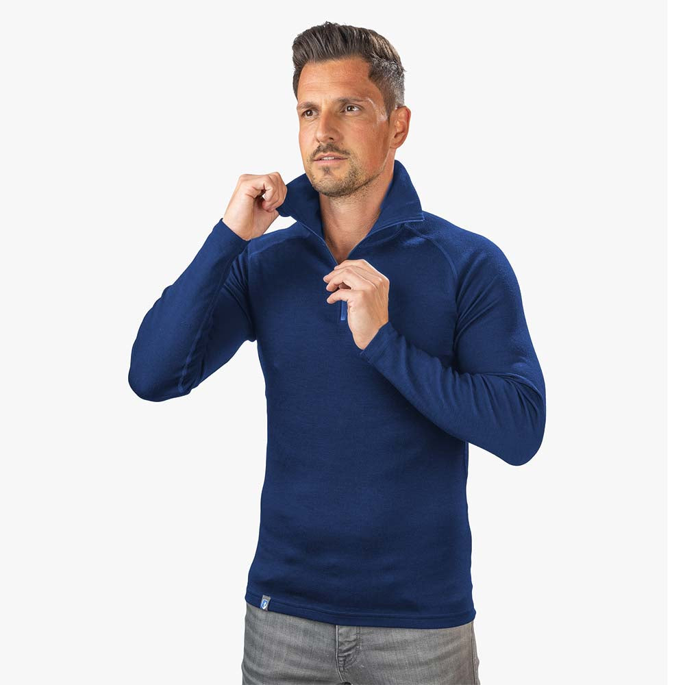 m², getragen von einem Mann. Perfekt für Outdoor-Aktivitäten, bietet Komfort und Funktionalität durch hochwertige Merinowolle.