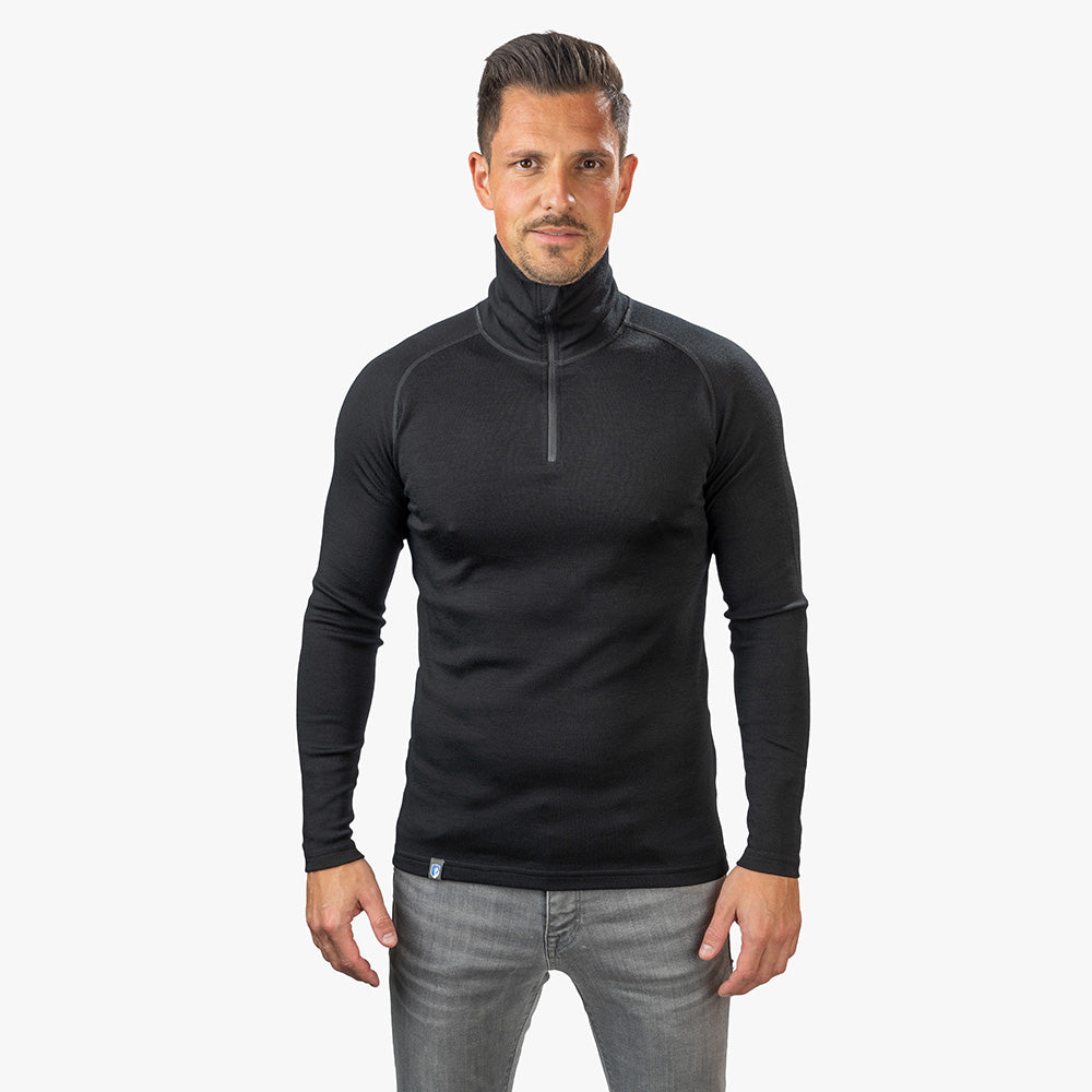 Merino Langarmshirt mit Zip Herren 230 g/m2: Mann in schwarzem Langarmshirt, ideal für Outdoor, aus 100% Merinowolle, atmungsaktiv und antibakteriell.