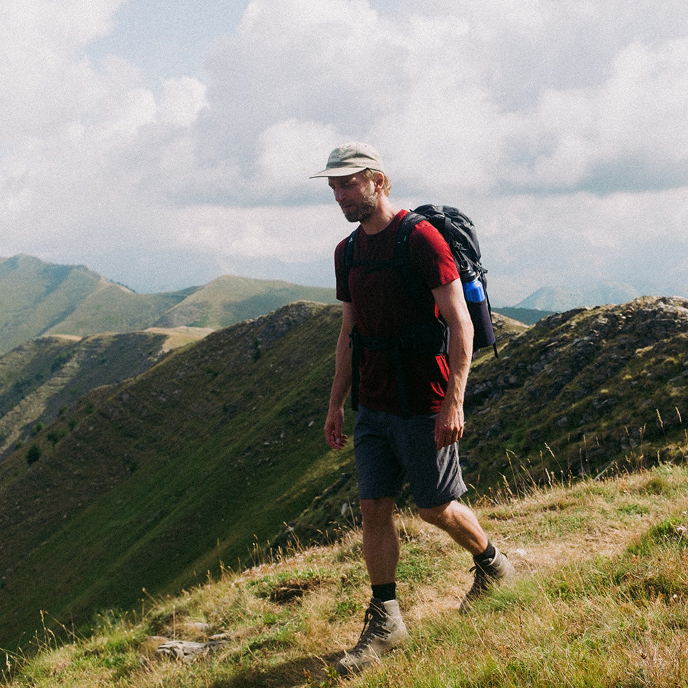 Mann auf Bergwanderung trägt das Merino T-Shirt Herren 150 g/m2, ideal für Outdoor-Aktivitäten, mit Rucksack und Hiking-Equipment sichtbar.
