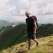 Mann auf Bergwanderung trägt das Merino T-Shirt Herren 150 g/m2, ideal für Outdoor-Aktivitäten, mit Rucksack und Hiking-Equipment sichtbar.