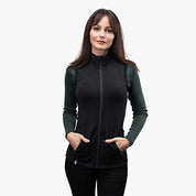 Frau trägt die Merino Weste Damen 270g/m2, eine sportlich geschnittene Wollweste mit Reißverschluss, ideal für Outdoor-Aktivitäten und kühle Tage.