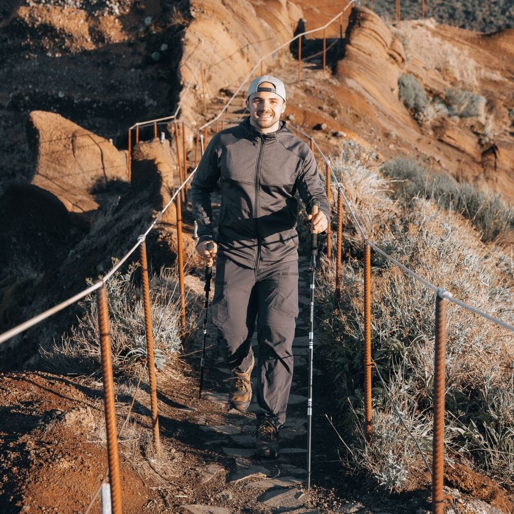Mann mit faltbaren Wanderstöcken aus Aluminium auf einer Seilbrücke; ergonomische Korkgriffe sichtbar, ideal für Outdoor-Abenteuer.