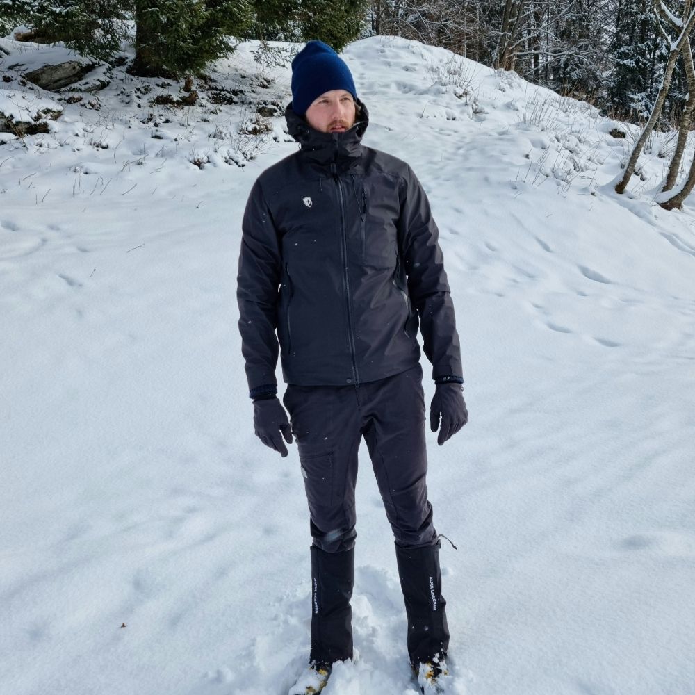 Mann im Schnee mit der Herren 3 Lagen Hardshell Regenjacke, ideal für Outdoor-Aktivitäten, wasserdicht, winddicht, atmungsaktiv. Perfekt für ganzjähriges Abenteuer.