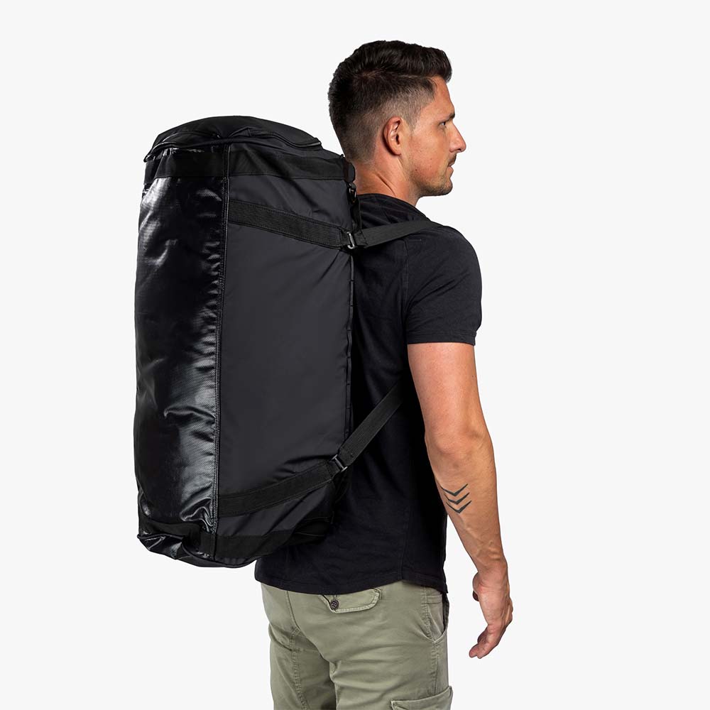 Ein Mann trägt die Reisetasche, Sporttasche & Duffel Bag von Alpin Loacker, wandelbar als Rucksack, ideal für Outdoor-Abenteuer.