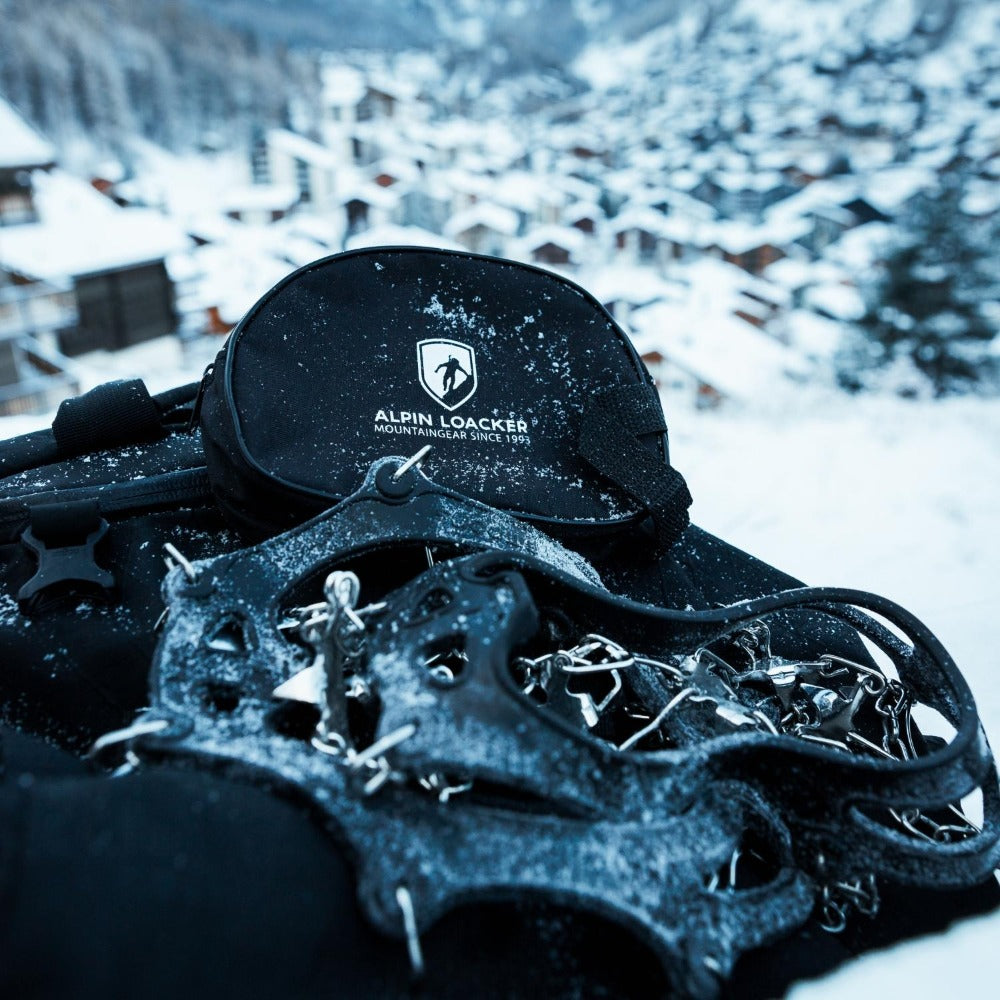 Chain Pro 18 Grödeln auf schwarzem Rucksack mit Schneeschuhen, ideal für sicheren Halt auf Schnee und Eis. Enthält 18 Spikes und praktische Aufbewahrungstasche.