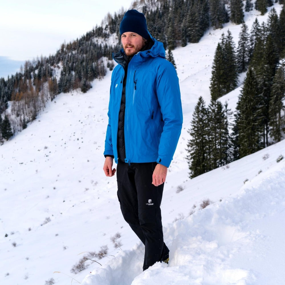 Mann im Schnee trägt Herren 3 Lagen Hardshell Regenjacke, ideal für Outdoor-Aktivitäten dank wasserdichter, winddichter und atmungsaktiver Eigenschaften.