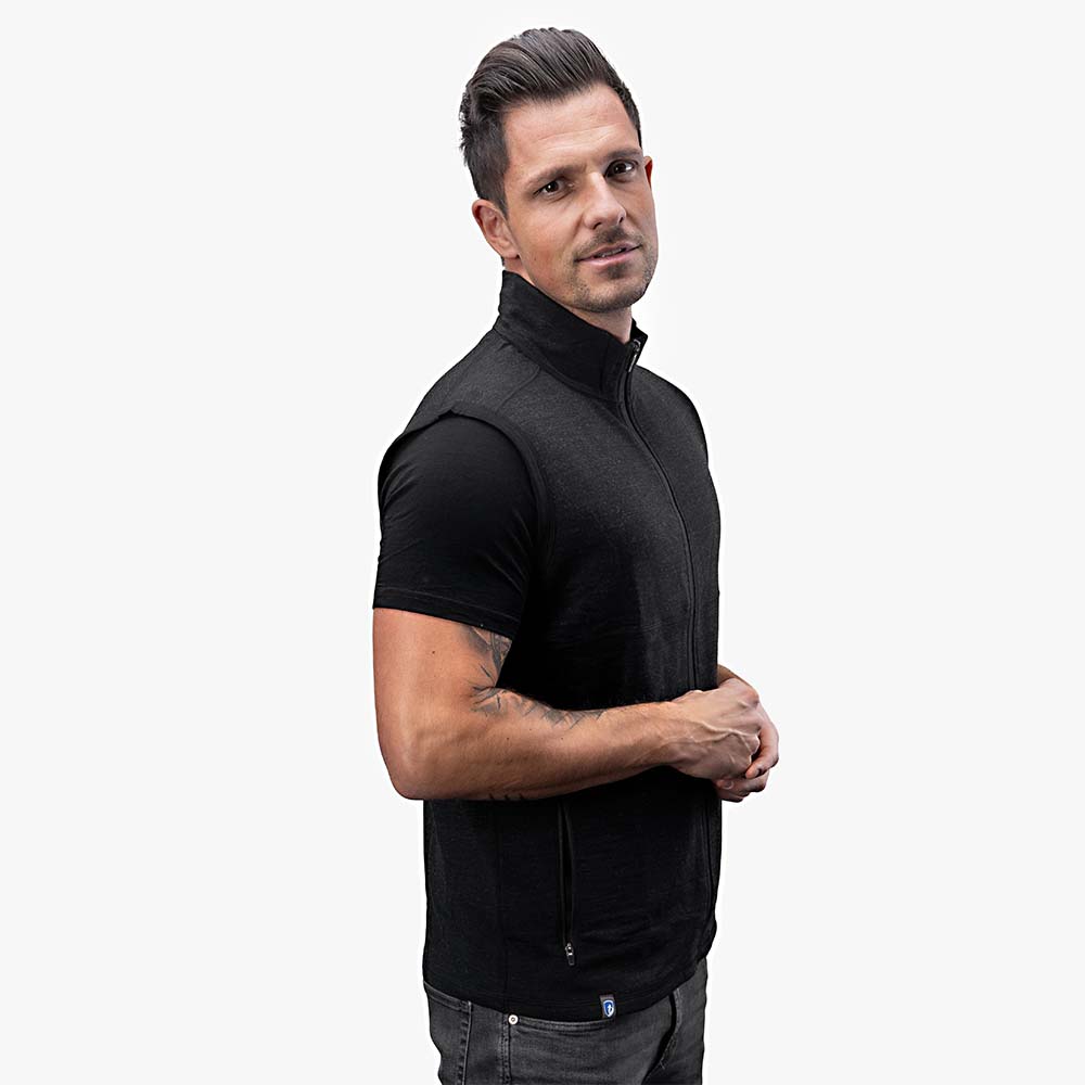 m²: Mann trägt schwarze Wollweste mit durchgehendem Reißverschluss, ideal als Midlayer für Outdoor-Aktivitäten und kühle Tage.