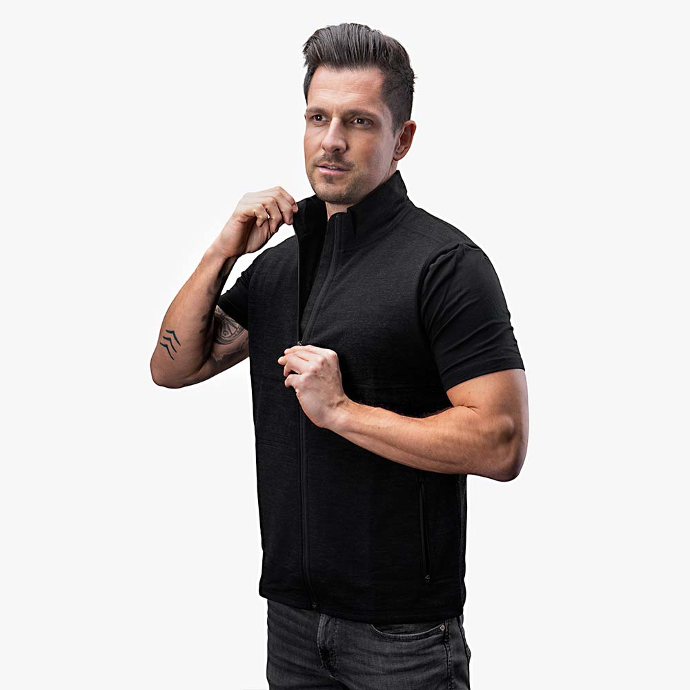 Merino Weste Herren 270 g/m²: Mann trägt stilvolle, schwarze Wollweste mit Reißverschluss, ideal für Outdoor-Aktivitäten und Freizeit. Perfekte Temperaturregulierung und hoher Tragekomfort.