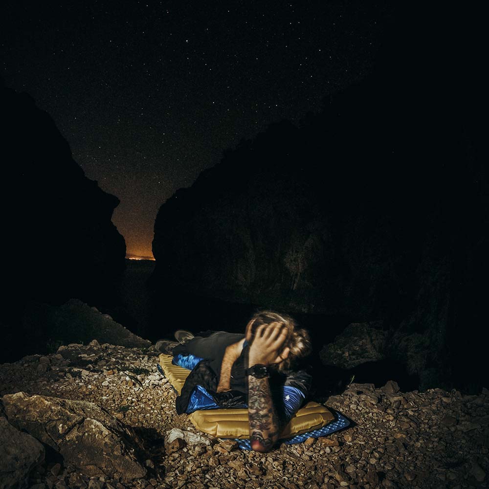 Mann liegt auf Ultraleichte Isomatte isoliert mit Kunstdaune - 460g in Höhle, ideal für Outdoor-Abenteuer und minimalen Rucksackplatzbedarf.