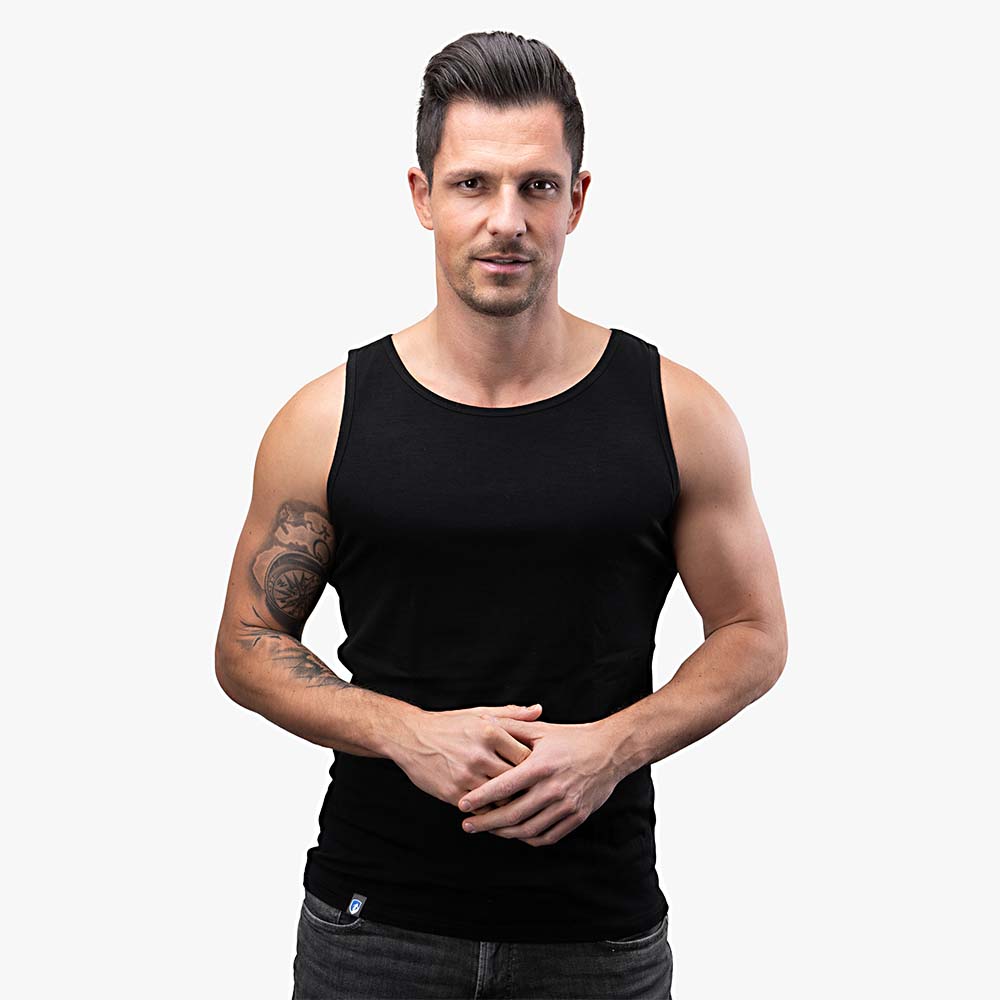 Mann in schwarzem CORESPUN Merino Tank Top Herren 150 g/m², ideal für Outdoor-Aktivitäten, kombiniert Merinowolle mit synthetischen Fasern für Komfort und Langlebigkeit.
