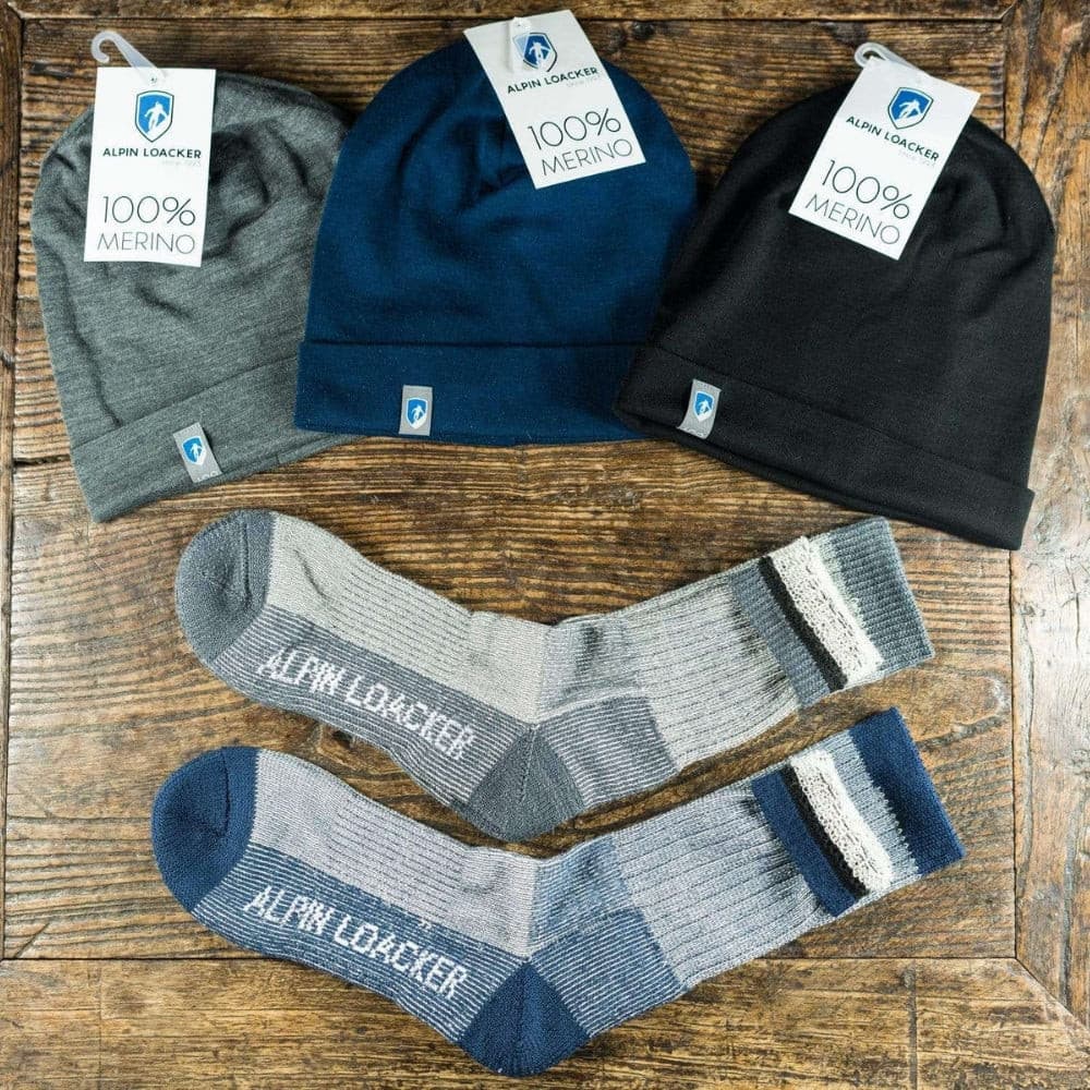 Merino Wandersocken Classic für Herren und Damen, aus 72% Merinowolle, ideal für Outdoor-Abenteuer. Abgebildet neben blauen und grauen Socken und Hüten.