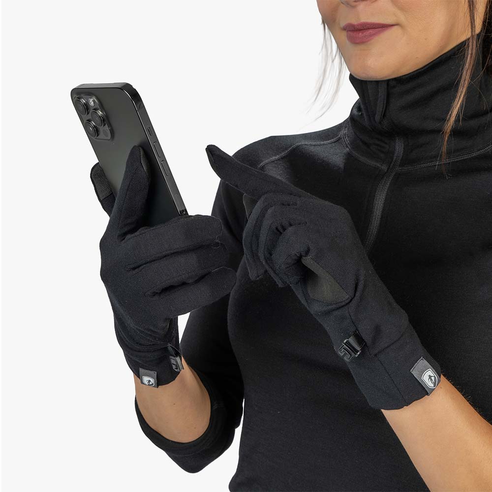 Eine Frau nutzt ein Smartphone mit Merino Handschuhe mit Touch Funktion, ideal für Outdoor-Aktivitäten durch Wärme, Komfort und Langlebigkeit.