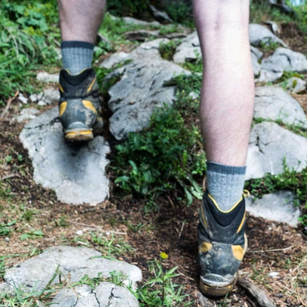 Merino Wandersocken Classic Herren & Damen auf Felsen getragen, ideal für Outdoor-Abenteuer. Socken bieten Komfort und Strapazierfähigkeit dank hohem Merinowollanteil.