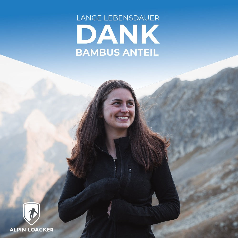 Frau in Merino Jacke Damen 270 g/m² lächelt vor Bergkulisse, ideal für Outdoor-Abenteuer und tägliche Nutzung durch Komfort und Atmungsaktivität.