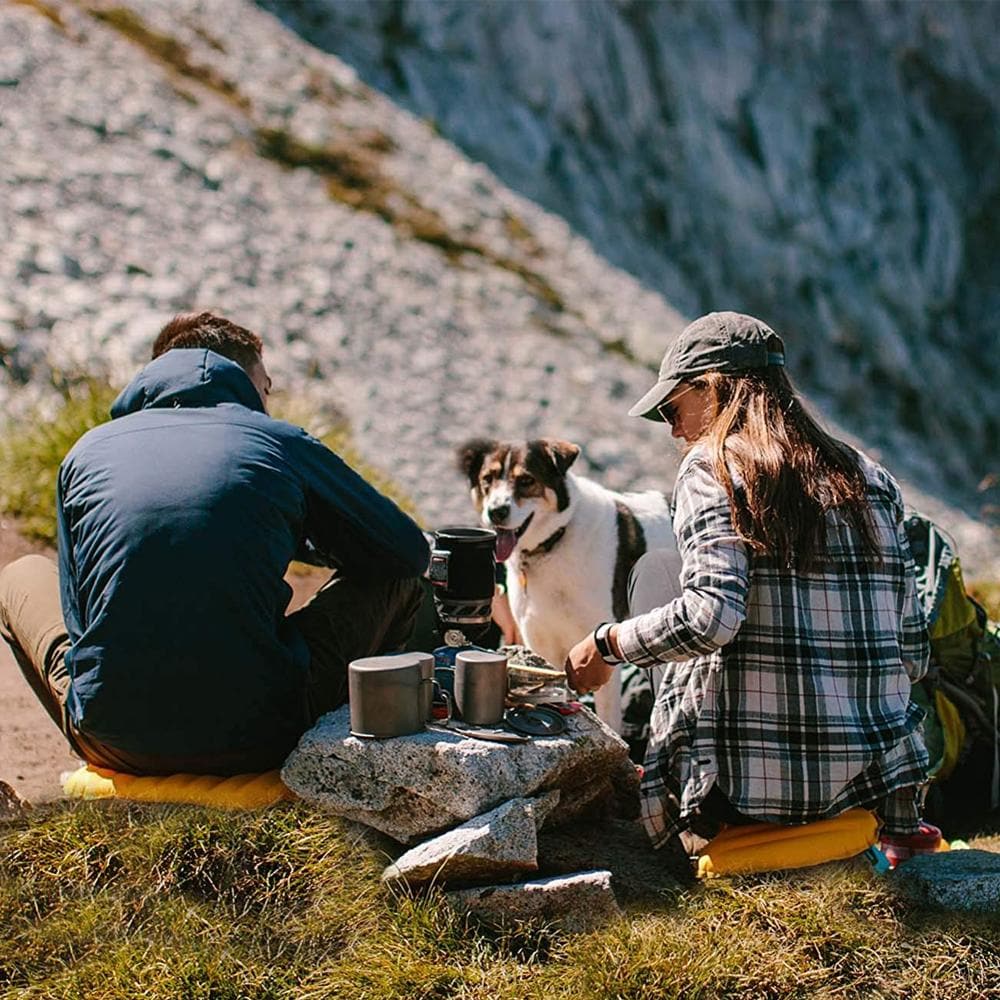 Personengruppe mit Hund auf Felsen, nutzt das Uni Sit Pad Pro Outdoor Sitzkissen, ideal für Camping und Reisen, kompakt und leicht aufblasbar.