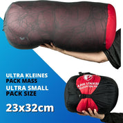 Person hält den Alpin Loacker Down Pro 4 Jahreszeiten Schlafsack, ideal für kalte Temperaturen und Trekking, bekannt für Leichtigkeit und Kompaktheit.