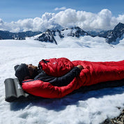 Mann schläft auf Schnee in einem Schlafsack, demonstriert die Leichte Isomatte isoliert mit Kunstdaune - 750g für optimalen Komfort und Isolierung beim Outdoor-Camping.