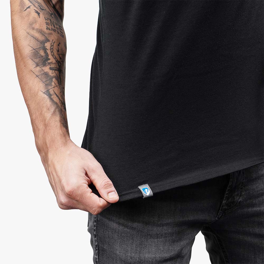 Mann trägt CORESPUN Merino Tank Top Herren 150 g/m², betont durch sichtbares Tattoo auf dem Arm, ideal für Outdoor-Aktivitäten, kombiniert Merinowolle mit synthetischer Robustheit.